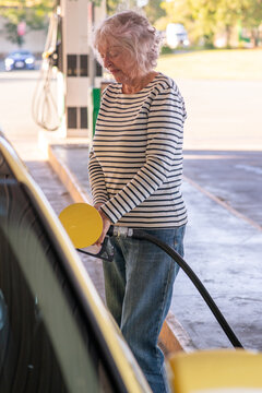 senior woman putting fuel in the car