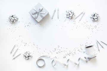 Festive party decoration in silver color with gift box and carnaval caps on white background, top view