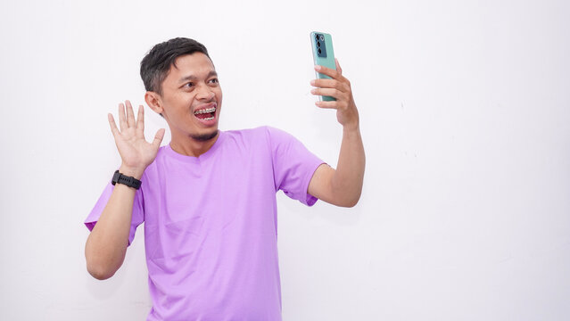 Asian Young Man Smiling and Waving During Video Call on Smartphone