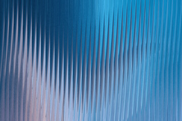 Abstract blue background with vertical ribbed texture and subtle light reflections creating a sense of depth and movement