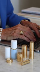 A closeup of a woman's hands typing on a laptop surrounded by white minimalist beauty products. 2
