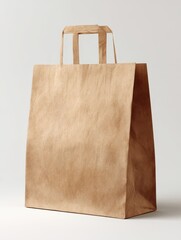 Simple brown kraft paper shopping bag with handles, standing empty and isolated on a plain white background.