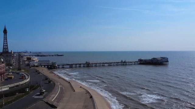 Aerial drone view of Blackpool seafront with the tower and all three piers at high tide in summer