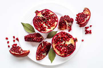 Plate full of fresh ripe pomegranate with cut in half and pieces, top view.