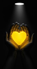 Hands holding a glowing yellow heart under a spotlight in the darkness.