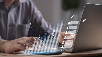 Close-up of businessman using laptop with virtual bar chart and rising graph, symbolizing financial growth, business analytics, digital marketing, data analysis, and economic success concept.