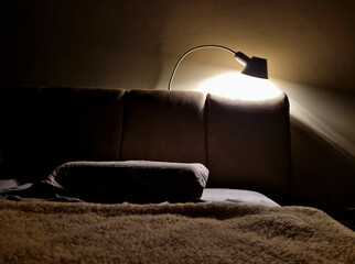 padding is a bed with a textile backrest. evening light from a lamp and warm light. cover, evening comfort before going to bed is a ritual of reading a fiction book