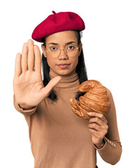 Young Filipina with Parisian look in studio standing with outstretched hand showing stop sign,...