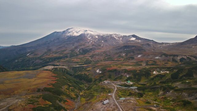 View of Mutnovsky Volcano (2,322 m) on the Kamchatka. Its peak is covered with snow, while the colorful lower slopes remain in autumn hues. Mutnovsky is one of the most active volcanoes in Kamchatka.