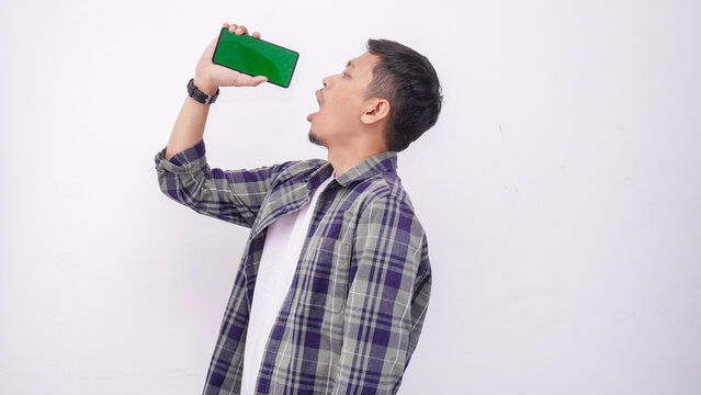 Man in Plaid Shirt Pretending to Drink from Smartphone with Green Screen - Powered by Adobe