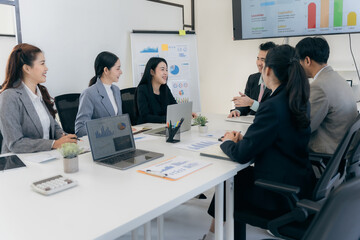 Group of business people discussing charts and graphs showing successful teamwork. Asian business team brainstorming meeting in office.