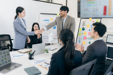 Group of Asian business people working together as a team to plan company strategy in brainstorming meeting at office. Casual business with startup teamwork concept, handshake concept.