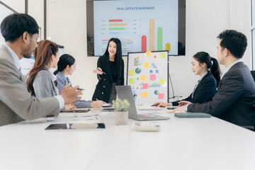 Group of business people discussing charts and graphs showing successful teamwork. Asian business team brainstorming meeting in office.
