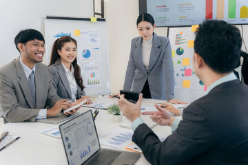 Fototapeta premium Group of business people discussing charts and graphs showing successful teamwork. Asian business team brainstorming meeting in office.