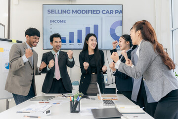 Group of happy Asian businesspeople congratulating each other to celebrate success in office conference room during meeting.