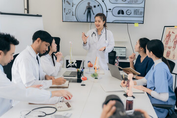 Fototapeta premium A group of young Asian physicians are talking with colleagues in a medical conference room, discussing and reviewing rare disease cases to improve practice guidelines. Doctors