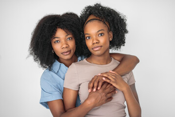 Affectionate mother and daughter portrait close to a white wall