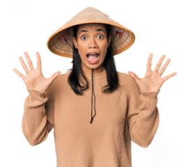 Young Filipina with Vietnamese hat receiving a pleasant surprise, excited and raising hands.