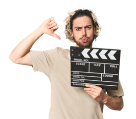 Young man with clapperboard in studio feels proud and self confident, example to follow.