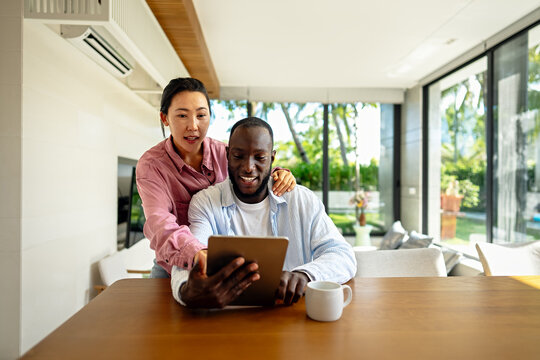 Happy multiethnic couple with laptop making plan for investments, savings and budget for bills