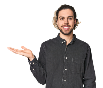 Young Caucasian man in studio setting showing a copy space on a palm and holding another hand on waist.