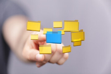 Hand choosing a blue folder from a group of yellow digital files.  Concept of data management, organization, and selection.