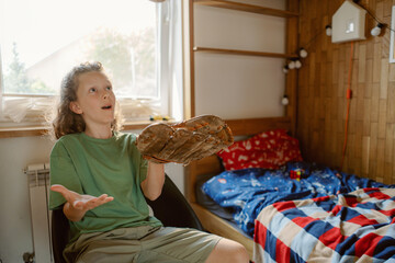 A young boy enthusiastically interacts while holding a baseball glove. He seems to express excitement, connecting with his family in a warm, inviting bedroom.