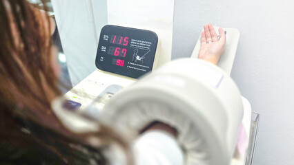 Blood pressure measurement with automatic digital monitor showing systolic, diastolic, and pulse rate, illustrating healthcare, prevention, diagnosis, and medical checkup in daily life.