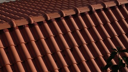 Close-up view of terracotta roof tiles in sunlight, showing texture, pattern, and warm earthy colors.