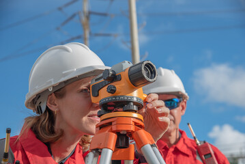 Construction workers using surveying equipment outdoors