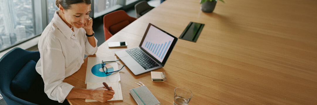 A businesswoman is diligently analyzing key financial data in a modern office environment - Powered by Adobe