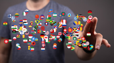 A person interacts with a digital display of various national flags, symbolizing global connection.