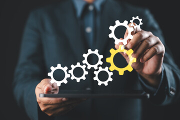 Business process management and solution. Businessman drawing connecting gears on tablet.