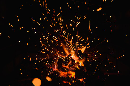 Fire embers particles over black background. Fire sparks background. Abstract dark glitter fire particles lights.