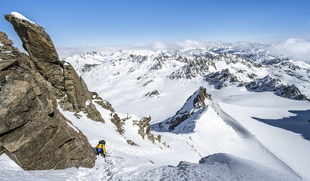 Mountaineer with ice axe and crampons, ascent through steep snowfield to Piz Kesch or Piz d'Es-cha in winter, view of mountain panorama with Vadret da Porchabella glacier, Albula Alps, Rhaetian Alps, Grisons, Eastern Switzerland, Switzerland