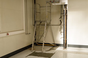 Stock photo of a metal ladder with safety platform in an industrial setting. Perfect for safety, construction, and industrial themes. © vegefox.com