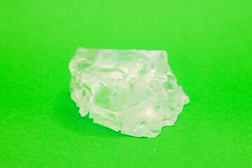 Fototapeta premium Large piece of crystal table salt on bright colored green background, close-up.