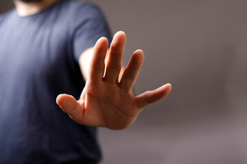 Obraz premium Close-up image of a man's hand gesturing to stop, conveying refusal, rejection, or caution. Perfect for concepts of denial, prohibition, and boundaries.