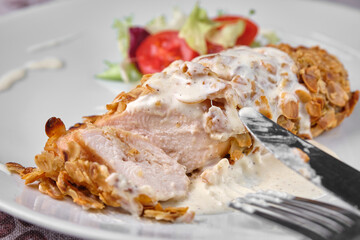 Delicious almond-crusted chicken breast with creamy sauce and fresh salad.
