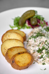 Delicious plate of roasted potatoes, dill sauce, and pickles.