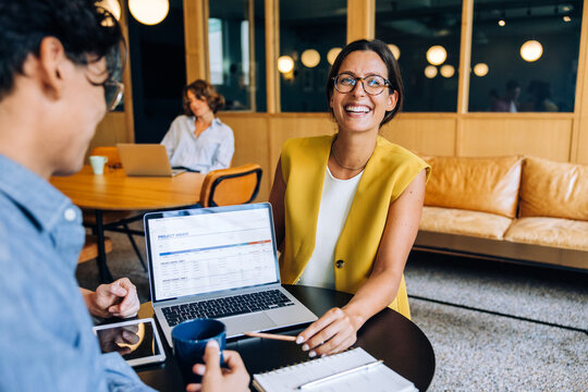 Smiling professional woman discussing a project in a modern office setting