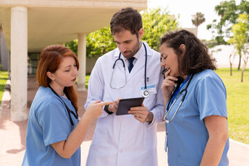 Medical professionals analyzing patient information on digital tablet, sharing clinical insights collaboratively