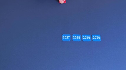 Man removes the figures of the years starting from 2025 and ending with 2030. The concept of the transience of life. New year, decade. Symbolism of time, a new beginning, the inevitability of change