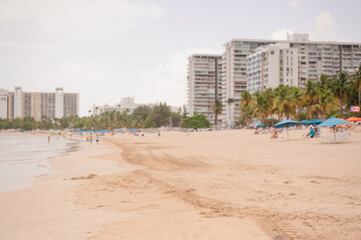Obraz premium People relaxing on Isla Verde Beach near tall buildings, Puerto Rico with copy space