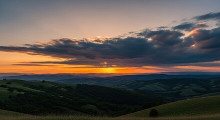 Obraz premium Mountain range silhouette at sunset, vibrant golden sky with clouds