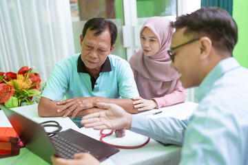 A doctor discusses health matters with a couple in a bright, welcoming clinic setting