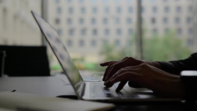 Man in a suit uses the touchpad on his silver laptop