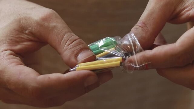 Closeup footage of hands taking out colorful shrink tubing from a small plastic bag