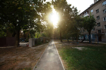 Afternoon sunlight filters through trees in a quiet urban park showcasing a peaceful walkway and playground