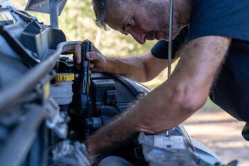 A mechanic with a flashlight checks a van's engine for a fault.
Transportation, trades, vehicles, person repairing